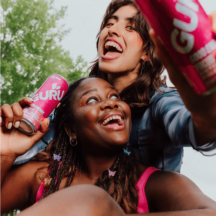 Friends holding GURU energy drinks outdoors